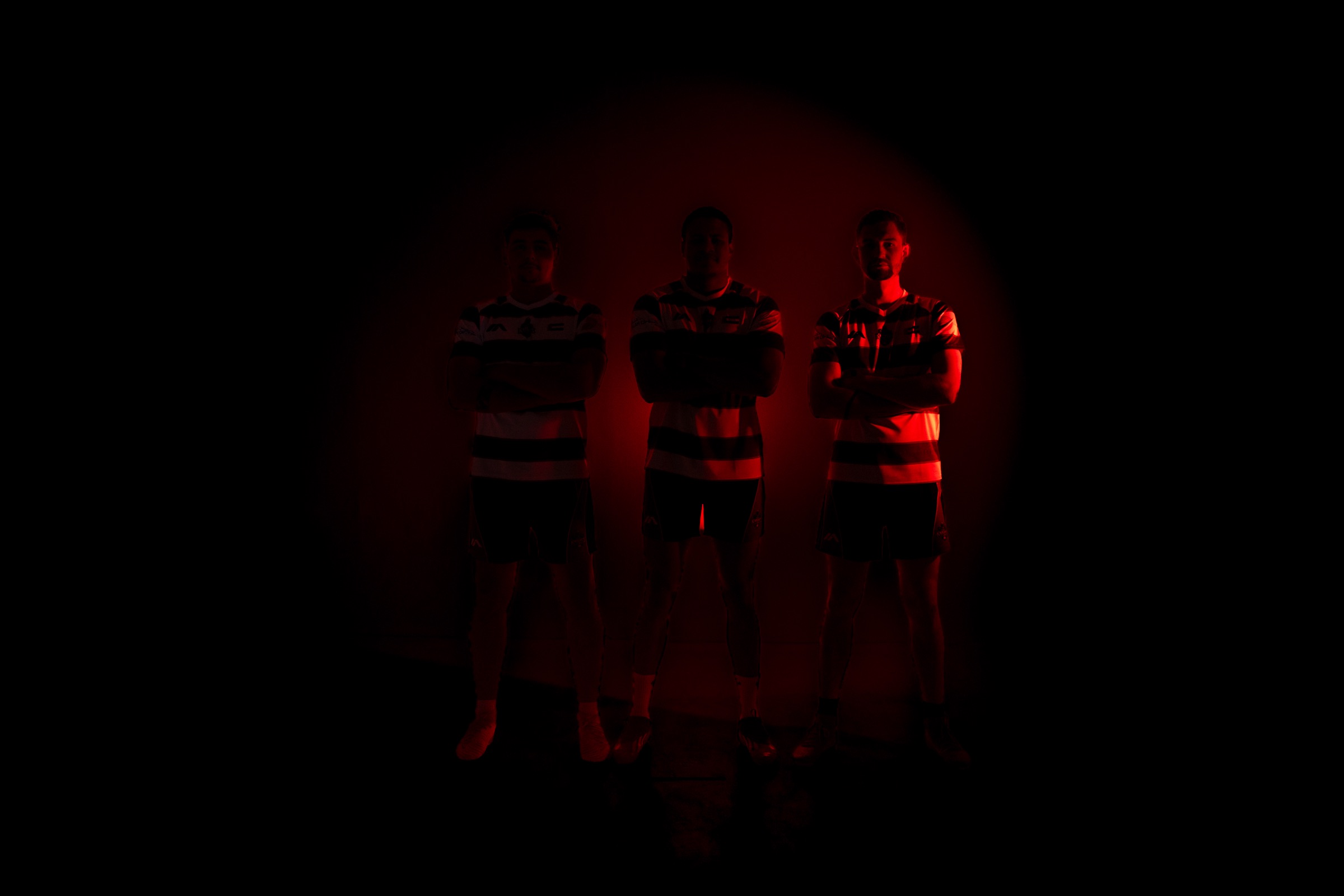 Three Dubai Knights players silhouetted in deep red light
